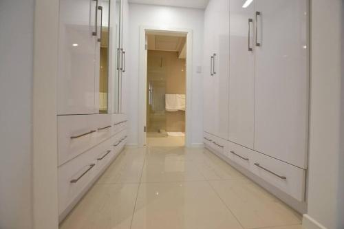 a white bathroom with white cabinets and a mirror at Skyview Apartments in Gaborone