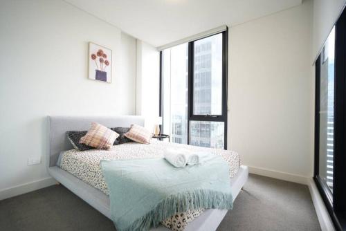 a white bedroom with a bed and a large window at High Level Luxury APT in Wentworth Point in Sydney
