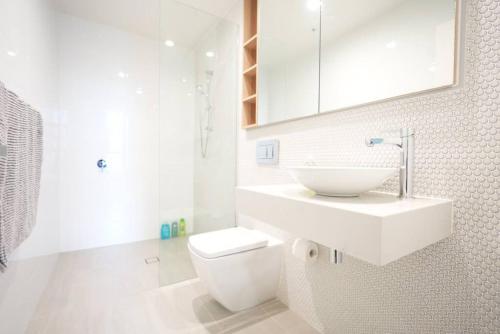 a white bathroom with a sink and a toilet at High Level Luxury APT in Wentworth Point in Sydney