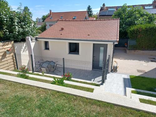 une petite maison blanche avec une clôture dans une cour dans l'établissement Petite maison cocooning aux portes de Paris, à Orly