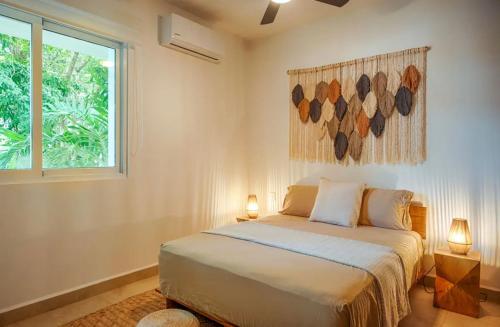 a bedroom with a bed with two lamps and a window at NEW! Boho chic condo, Aldea Zama in Tulum