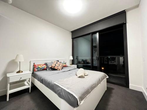 um quarto com uma cama e uma grande janela em Lovely 2 bedroom APT in centre of Olympic Park em Sydney