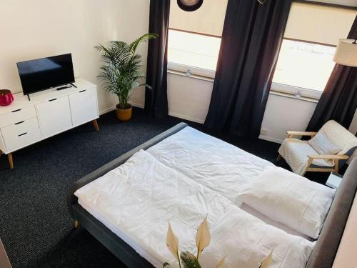 1 dormitorio con 1 cama, TV y silla en Ferienwohnung Edge-Inn, 