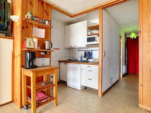 une petite cuisine avec des armoires blanches et une table dans l'établissement Grand studio cabine accès plage parking privé - FR-1-715-16, à Mauguio