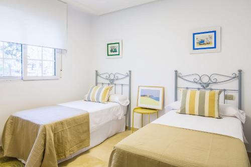2 camas en una habitación con paredes blancas en OleHolidays Gala junto a Puente Romano en Marbella