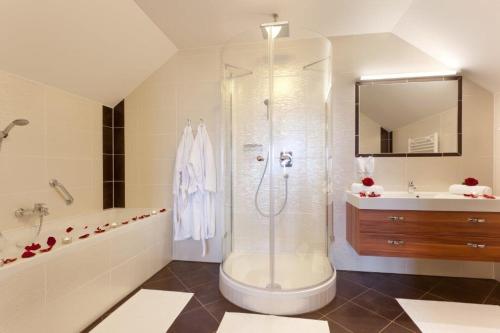 a bathroom with a shower and a tub and a sink at Panorama Hotel Gasthof Leidingerhof in Mondsee