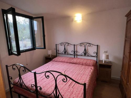 una camera da letto con un letto con copriletto rosso e una finestra di Casa Chia a 5 minuti dal mare - Su Giudeu Tuerredda a Chia