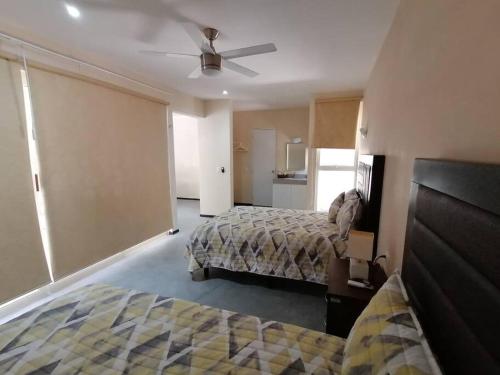 a bedroom with two beds and a ceiling fan at beachfront apartament next to nomads d1 in Isla Mujeres