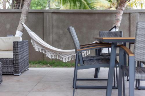 a table and chairs and a hammock on a patio at Serenity Residences & Spa - Kokrobite Beach in Kokrobite