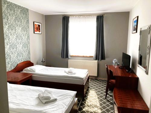 a hotel room with two beds and a desk and a window at Hotel Ava in Gliwice