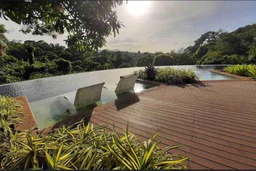 - une piscine avec 2 chaises sur une terrasse en bois dans l'établissement Staycation @ Sandari Batulao, à Tagaytay