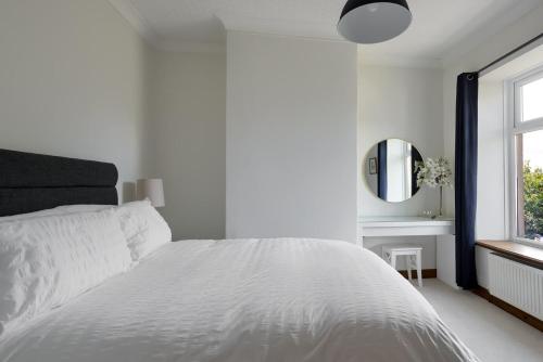 biała sypialnia z białym łóżkiem i lustrem w obiekcie Bar Cottage Number 2 w mieście Altham