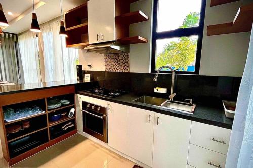 a kitchen with white cabinets and a sink and a window at Staycation At Sandari Batulao Overlooking Spot in Tagaytay