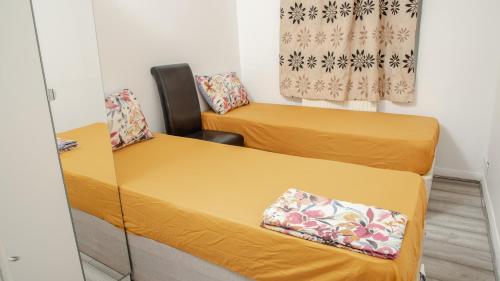 two beds in a small room with yellow sheets at Floral, 5 Bed House in London with Garden, Parking in Dagenham