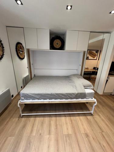 uma cama branca num quarto com piso em madeira em Studio Contemporain, À Deux Pas de la Mer à La Ciotat ! em La Ciotat