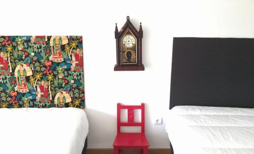 a bedroom with a clock and a red chair at Meio Country House in Alcanede