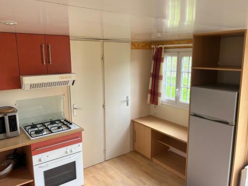 a small kitchen with a stove and a refrigerator at Camping Les Portes de la Baie de Somme in Mareuil-Caubert