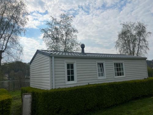 una pequeña casa blanca con techo en un patio en Camping Les Portes de la Baie de Somme, en Mareuil-Caubert