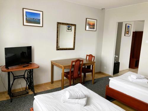 Habitación con 2 camas y mesa con TV. en Hotel Ava, en Gliwice