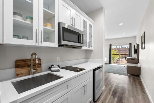 a kitchen with white cabinets and a sink at Cedar Street Hotel & Suites in Sandpoint