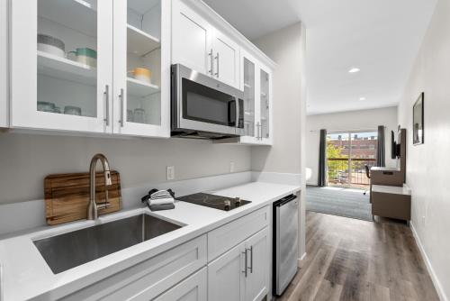 a kitchen with white cabinets and a sink at Cedar Street Hotel & Suites in Sandpoint