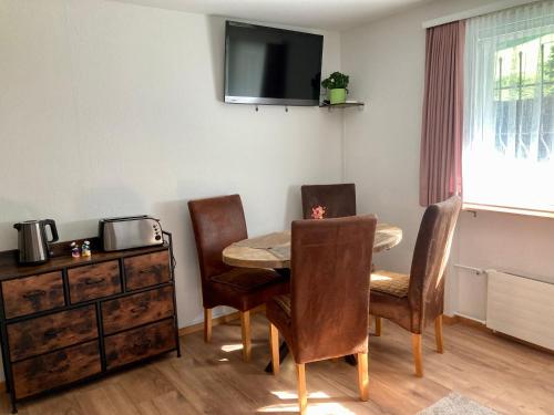 Zimmer mit einem Tisch und Stühlen sowie einem TV an der Wand in der Unterkunft Ferienwohnung Haus am Bach in Toggenburg in Wildhaus