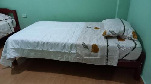 Bett mit weißer Decke in einem Zimmer in der Unterkunft ALOJAMIENTO ANY in Tingo María