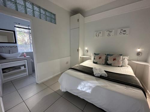 ein weißes Schlafzimmer mit einem Bett und einem Waschbecken in der Unterkunft The Owl on 5th in Port Elizabeth