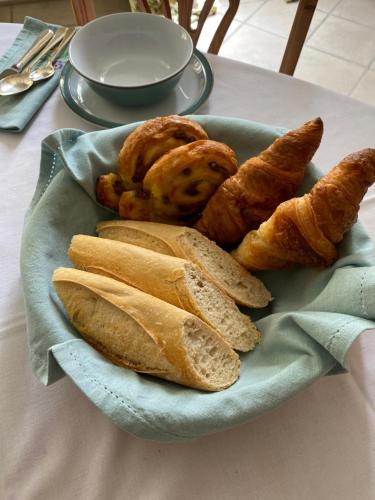 un plato de pan y bollería en una mesa en Le Manoir aux Volets Verts with Hot Tub, en Salerm