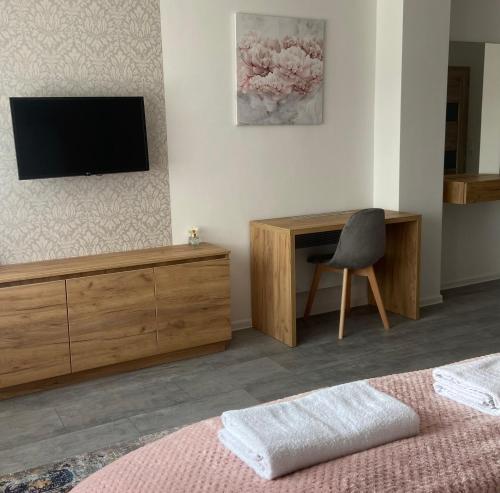 a bedroom with a tv and a desk and a chair at Martin Apartmanok in Bük