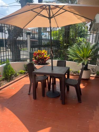 a table and chairs with an umbrella on a patio at CASA HOTEL FLOR DEL VALLE in Cali