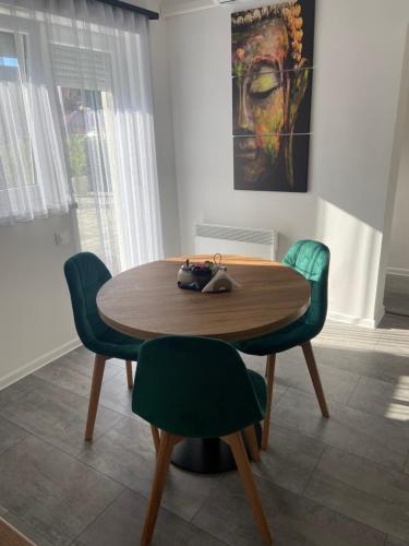 a dining room table with two green chairs at Martin Apartmanok in Bük