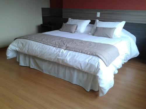 a bedroom with a large bed with white sheets and pillows at Matsubara Pousada in Campos do Jordão