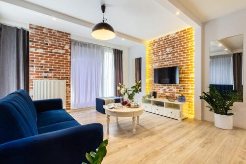 a living room with a blue couch and a brick wall at AbsyntApart Krawiecka - Just in Center Wrocław Rynek - MAMY WOLNE POKOJE ! in Wrocław