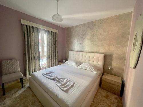 Un dormitorio con una cama blanca y una silla. en S&E Apartment, en Tushemisht