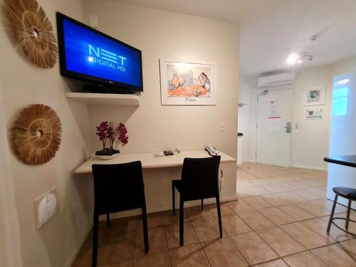 a room with a desk with chairs and a tv on the wall at Belle Arti Pousada in Florianópolis