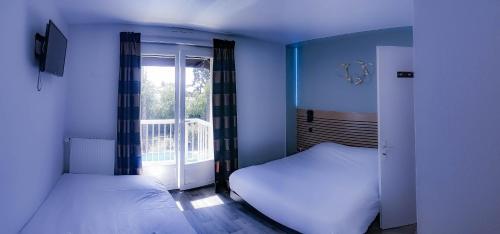2 camas en una habitación con ventana en Logis Les Charmilles Chalon-sur-Saône Sud, en Lux