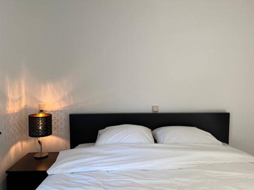 a white bed with a black headboard and a lamp at The coffee Corner Nuenen/Eindhoven in Nuenen