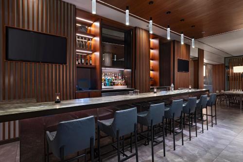 a bar in a restaurant with chairs and a television at AC Hotel by Marriott Houston Downtown in Houston