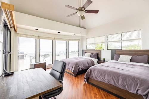 two beds in a bedroom with a table and a ceiling fan at Oceanview Luxury Villa Pool & SPA in Kailua-Kona