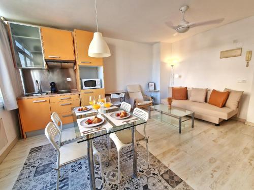 uma cozinha e uma sala de estar com mesa e cadeiras em Confortable Apartamento en el Centro de Torremolinos con Parking em Torremolinos