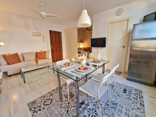 uma sala de estar com uma mesa de vidro e cadeiras em Confortable Apartamento en el Centro de Torremolinos con Parking em Torremolinos