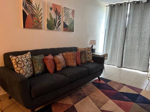 a black couch with colorful pillows in a living room at Lovely 2 bedroom condo with pool and beach access in Rincon