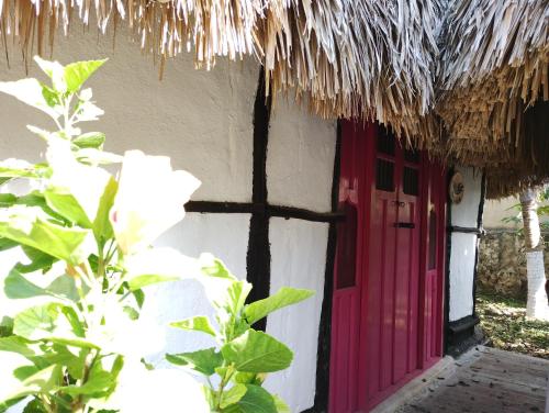 a house with a red door and a thatch roof at Hotel y Museo Aldea Maya Toktli Orígenes - Suite La Casa Maya - Alberca, Wifi Starlink, Tour Museo in Izamal