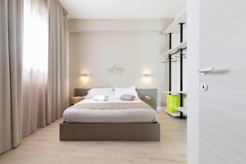 a white bedroom with a bed and a window at La Locanda d'Oro in Monastir