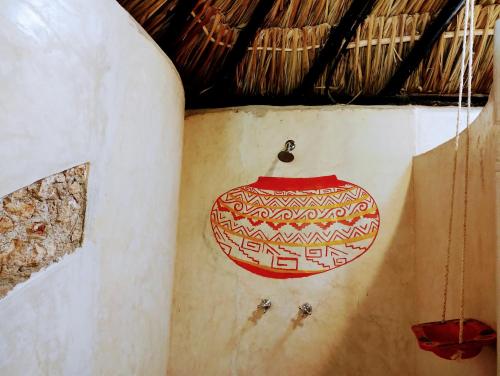a red pot hanging on the side of a wall at Casa Maya - Alberca - Wifi Starlink - Tour Sostenibilidad in Izamal