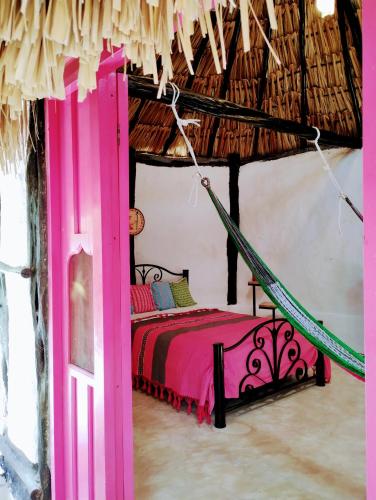 a bedroom with a pink bed in a room at Hotel y Museo Aldea Maya Toktli Orígenes - Suite La Casa Maya - Alberca, Wifi Starlink, Tour Museo in Izamal