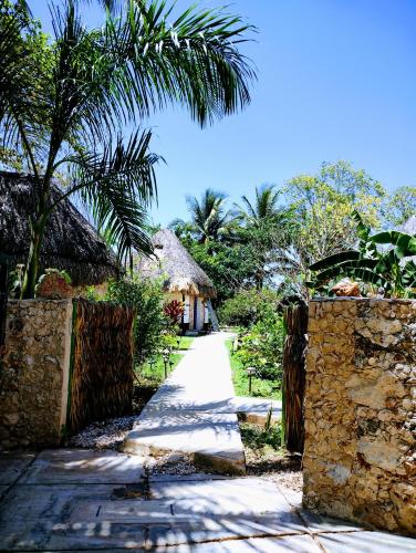 a path leading to a house with a palm tree at Hotel y Museo Aldea Maya Toktli Orígenes - Suite La Casa Maya - Alberca, Wifi Starlink, Tour Museo in Izamal