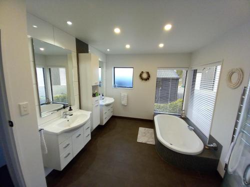uma casa de banho com 2 lavatórios, uma banheira e um WC. em Palms on Bruntwood em Tamahere