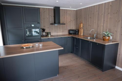 a kitchen with black cabinets and a wooden floor at Furetoppen Panorama in Stryn